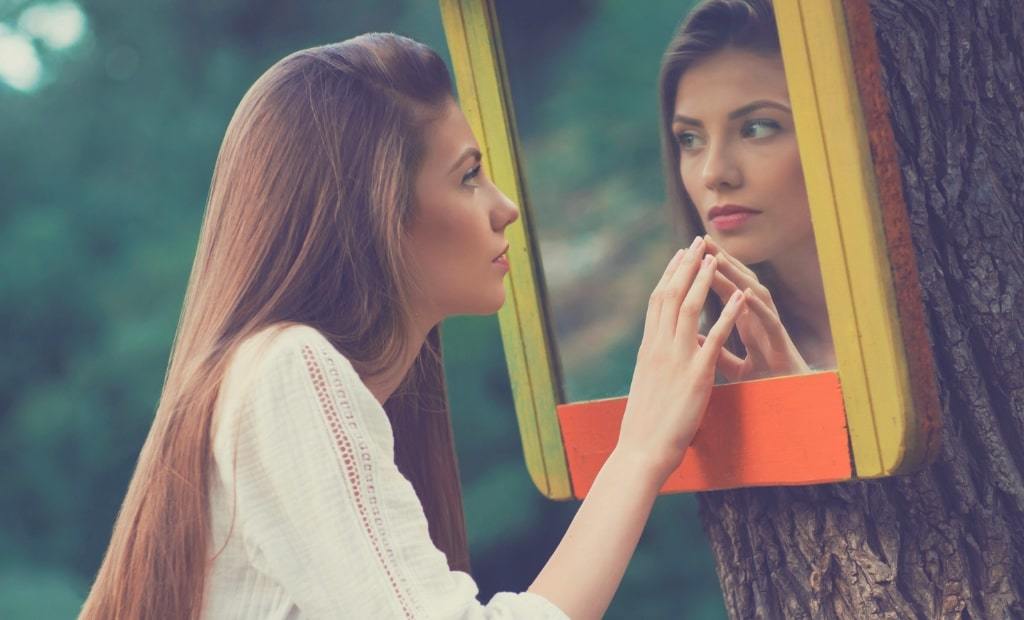 Learn how to love yourself in these 16 ways to love yourself with image of a girl looking at the mirror.